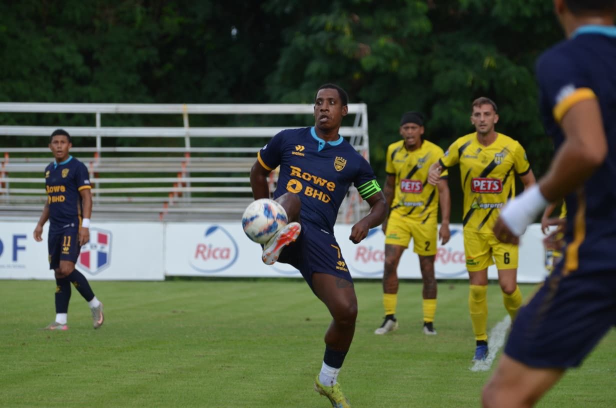 Luis Espinal de Pantoja ante la mirada de los jugadores de Moca FC, en acción de la LDF